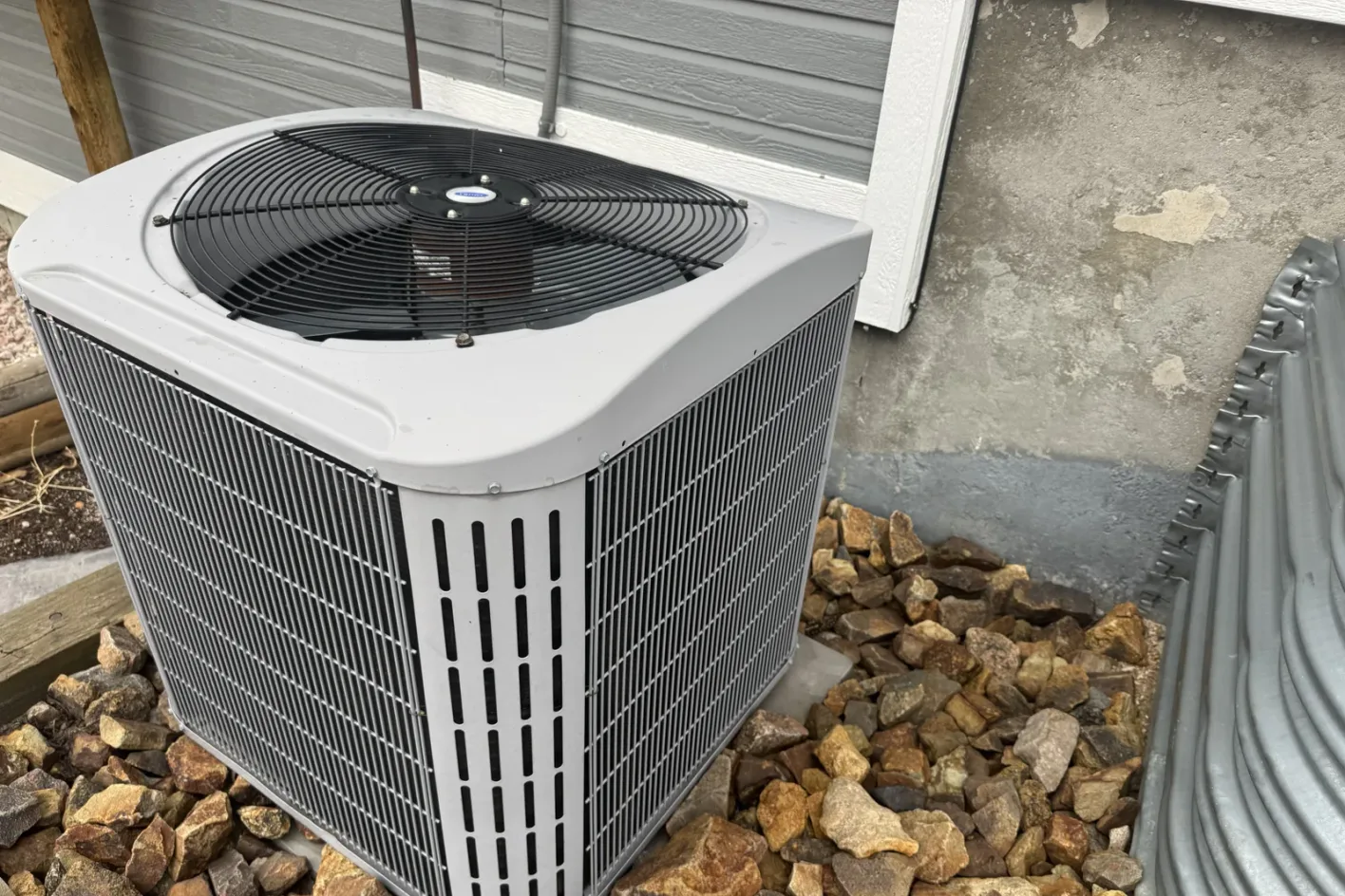 An outdoor condenser unit set in landscape rock beside a Colorado home, the kind of outdoor unit a heat pump installation uses